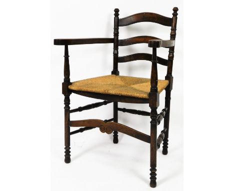 A 19thC country ladder back chair, with rush seat, turned arms, ring turned front legs joined by double side stretchers, with