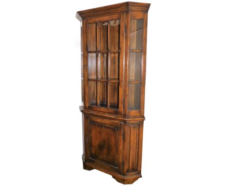 A 20thC oak free standing corner cupboard, in the manner of Titchmarsh and Goodwin, the upper section with glass panels raise