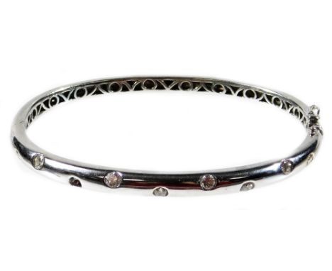 A modern 18ct white gold and diamond set hinged bangle, the top half designed with nine round brilliant cut diamonds (one mis
