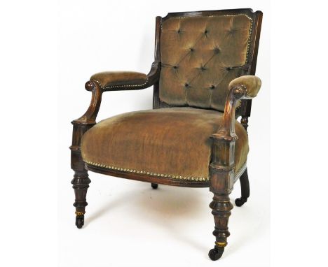 An Edwardian oak stained occasional chair, with button back overstuffed arms and seat, with inverted arm supports and turned 