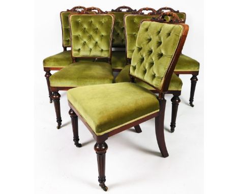 A set of six early Victorian mahogany library or dining chairs, each with overstuffed button backs and seats, carved scroll a