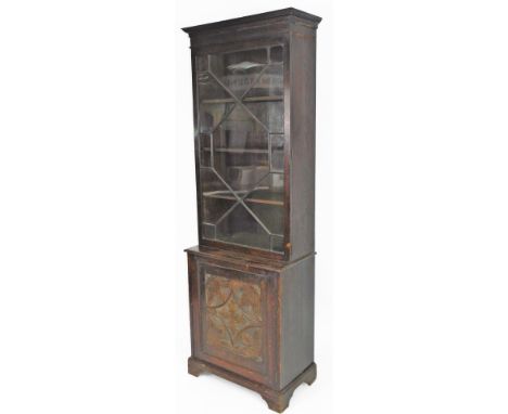 A 19thC oak stained narrow bookcase, with fixed carved cornice, raised above a single astragal glazed door, with carved panel