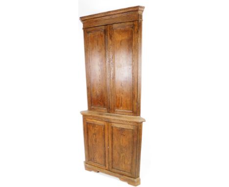 A 19thC oak free standing corner cupboard, the upper section with two panelled doors revealing shelves above a similar arrang