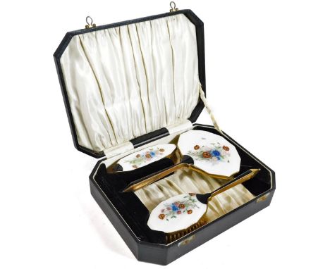 A cased enamel dressing table set, comprising hairbrush, 24cm W, clothes brush and hand mirror, each with a floral enamel on 