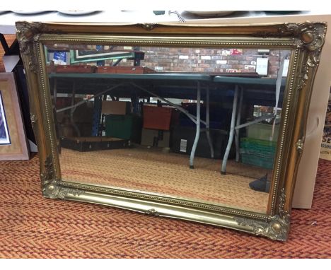 A LARGE ORNATE GILT FRAMED MIRROR 106CM X 76CM 