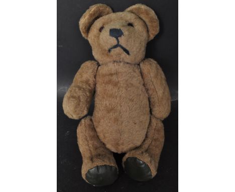 A retro vintage 20th century circa 1950s teddy bear having fully adjustable head and limbs with amber stone eyes. Measures 33