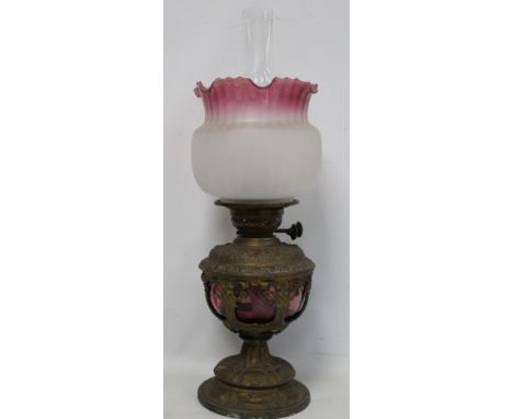 Victorian oil lamp, the cranberry glass reservoir in moulded spelter holder with domed foot, with pink and white frosted glob