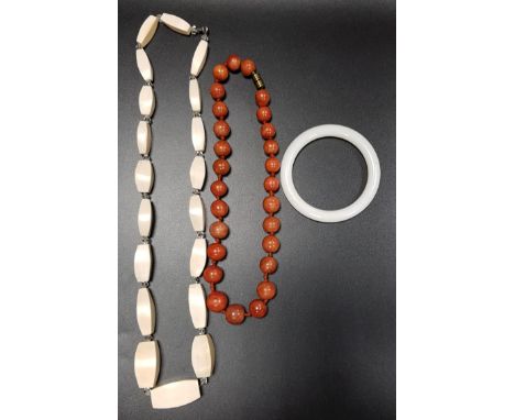 IVORY BEAD NECKLACEwith graduated lozenge shaped beads, a white jadeite bangle and a graduated orange bead necklace (3) 