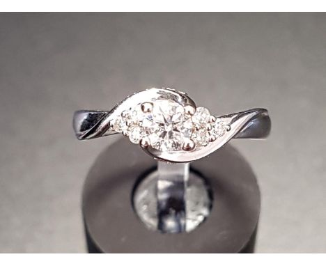 PRETTY TWIST SET DIAMOND RINGthe central round brilliant cut diamond flanked by three small diamonds to each side and with fu