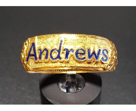 TWENTY-THREE CARAT GOLD DRESS RINGwith enamelled 'Andrews' flanked by motif and scroll decorated shoulders, marked '96.5%TU1'