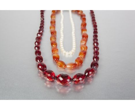 A GRADUATED FACET CUT BEAD NECKLACE of scarlet translucency, TOGETHER with a Cornelian bead NECKLACE with silver and Cornelia