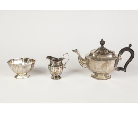 A LATE VICTORIAN SILVER COMPOSITE THREE PIECE TEA SERVICE, each of panelled form, the TEAPOT with leaf carved blackwood handl