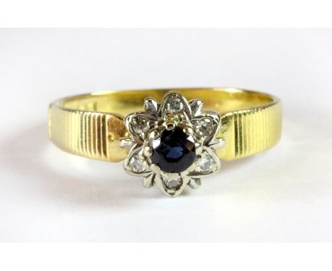 An 18ct yellow and white gold sapphire and diamond cluster ring (O).