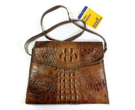 A vintage crocodile skin handbag, with an old British Calaedonian cabin bag label.