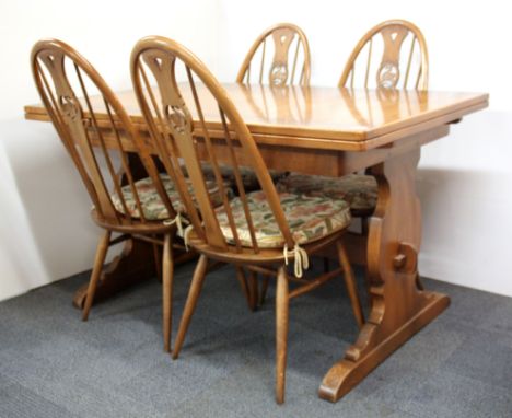 A 1970's Ercol extending dining table and four swan backed chairs, table closed length 137cm, open length 205cm.