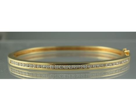 18CT GOLD DIAMOND SET BANGLE. The thirty three diamonds channel set with safety clasp. Weight 18.3g approx. (B.P. 24% incl. V