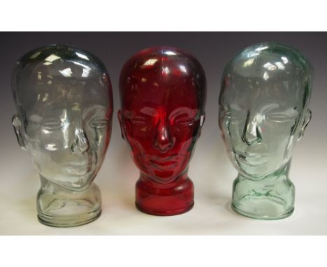 A pair of 20th century moulded pressed clear glass mannequin head, 29cm high; another ruby glass (3)