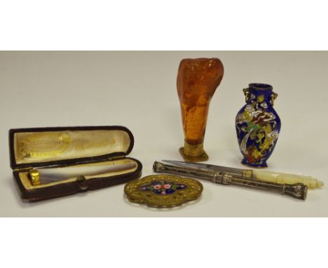 An early 20th century gold coloured metal mounted mother of pearl cigarette holder; an amber desk seal; a silver coloured met