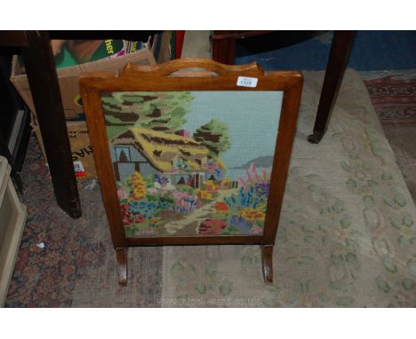 A wooden Firescreen with embroidered cottage scene