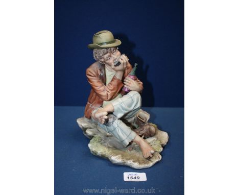 A Capo-de-Monte figure of a tramp with a bottle in is hand playing a harmonica.