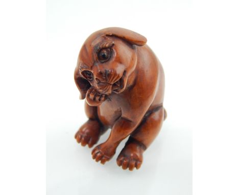 A netsuke carved as a seated dog, bears signature to base. 