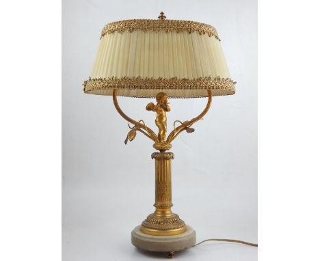 An early 20th century table lamp, the base with gilt foliage centred by cherub playing the flute above column base, raised on