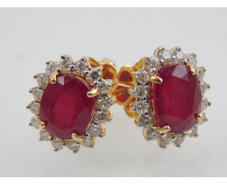 A pair of 18ct yellow gold and ruby cluster earrings, the oval cut ruby of 6.17ct, diamonds of 0.73ct combined.  