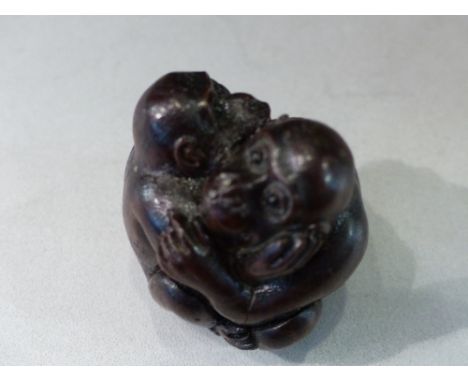 A hardwood netsuke, modelled in the form of embracing monkeys, H. 4cm.