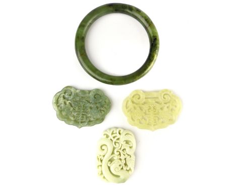 Three Chinese carved jade ''bi'' form pendants ranging from white to spinach, sold together with a jadeite bangle. (4)