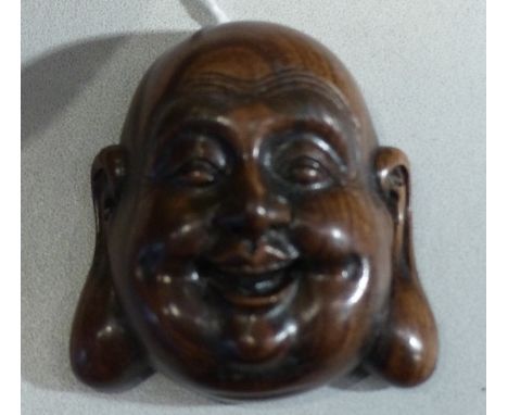 A carved hardwood netsuke, modelled in the form of a happy monk, the reverse bearing a signed disk, H. 5cm