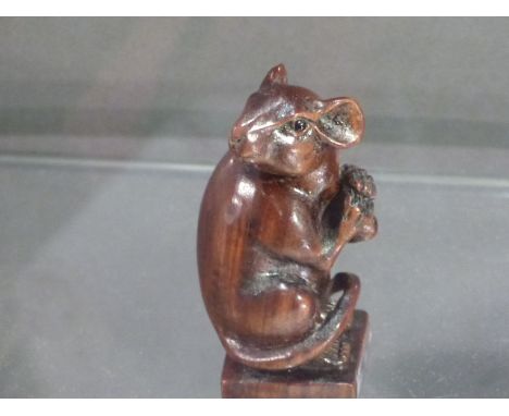 A hardwood netsuke, carved in the form of a rat, the base bearing a signature disk, H. 6cm. 