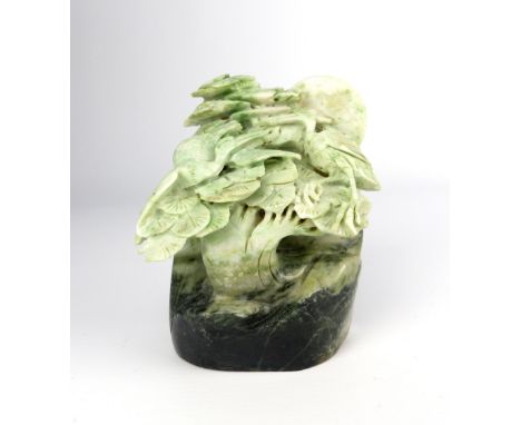 A Chinese carved variegated green jade paperweight depicting cranes amongst prunus trees, 9.5cm high.