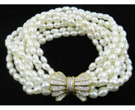 An eight strand pearl bracelet, having an 18 carat yellow gold and diamond bow-shaped clasp. 