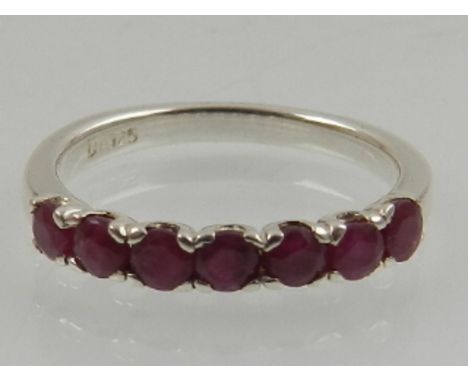 A silver and ruby ring, set seven round cut stones. 