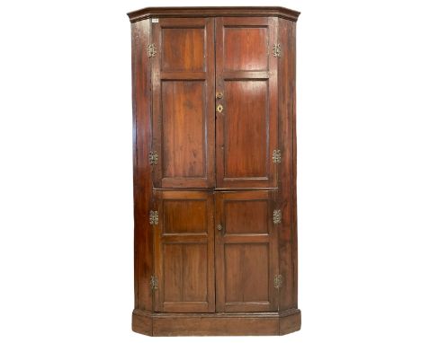 George III stained pine double corner cupboard, the projecting cavetto cornice over four panelled cupboard doors, the top sec