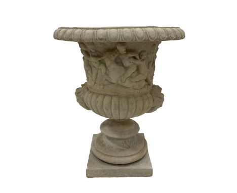 Composite stone Campana shaped garden urn, the egg and dart edge over a relief frieze depicting mischievous putti and bacchic