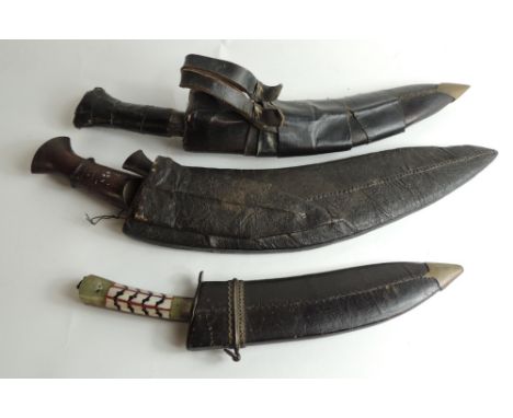 A Kukri with wood handle, the blade with foliate detail to the back, in leather scabbard and with single small knife; another