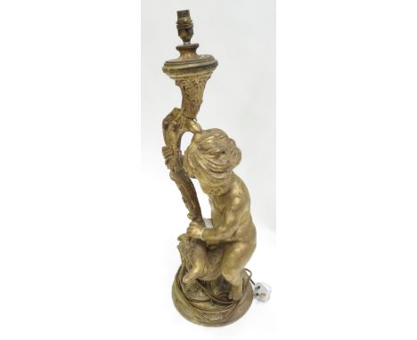 A decorative gilt gesso composition table lamp in the form of a putto holding a foliate branch, on circular base, 71cm high