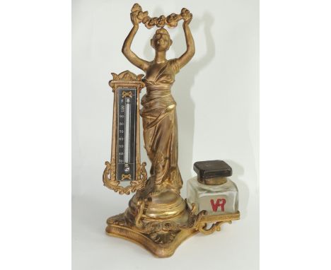 A Victorian gilt metal desk stand cast as figure of classical woman and with thermometer, pen holder and glass ink bottle imp