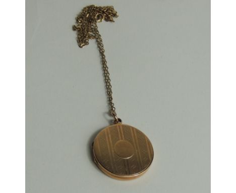 A 9 carat gold locket, Birmingham 1918, of circular outline and with engine turned decoration, 2.8 cm diameter; on a chain, 1