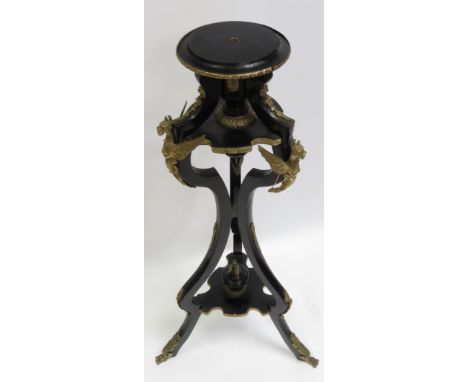 An ebonised and brass stand in Empire style, of tripod form with circular top and with applied cast brass mounts and edging, 