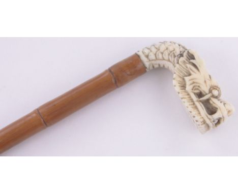 A Chinese ivory and bamboo cane circa 1900,with carved dragon's head finial, length 77cm.