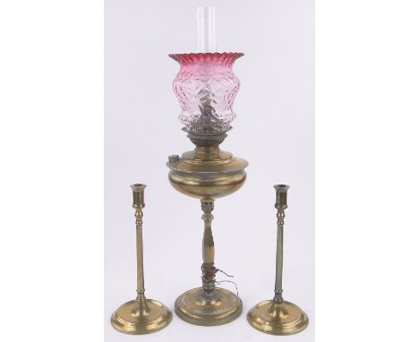 A Juno brass oil lamp,with Cranberry frilled glass shade, converted to electric and a pair of 19th century brass candlesticks