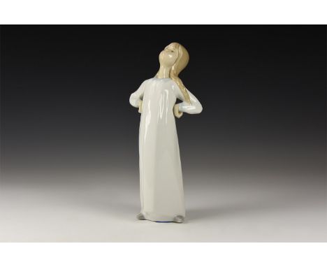 20th century AD. A hollow-formed glazed ceramic figure of a standing girl with hands on hips; marked 'Lladro' to the undersid