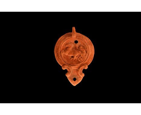An undated archaistic ceramic redware oil lamp in 1st-2nd century AD style, with pointed nozzle and pelta shaped volutes to t