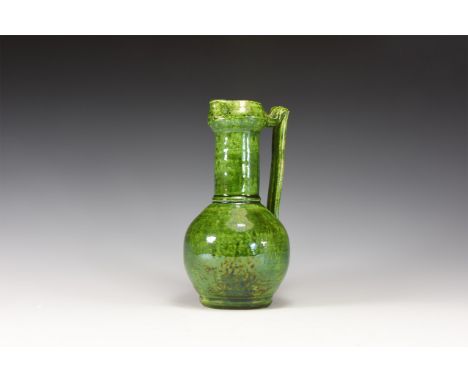 20th century AD. A green glazed stone ware jug with pinched rim for spout, long neck with collar to base; globular body with 