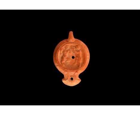 An undated archaistic ceramic redware oil lamp in 2nd-3rd century AD style, with rounded nozzle and pelta shaped volutes; ang