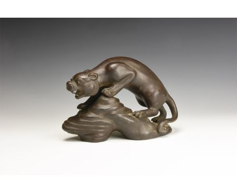 20th century AD. A ceramic figurine of a feline preparing to leap from a rocky platform; maker's mark to the underside.  751 