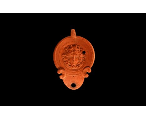 An undated archaistic large ceramic redware oil lamp in 1st-2nd century AD style, with rounded nozzle and pelta shaped volute