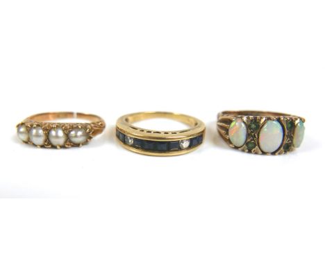 A group of three gold rings, comprising a 9ct yellow gold dress ring set with three oval opals, largest 7 by 4mm, separated b